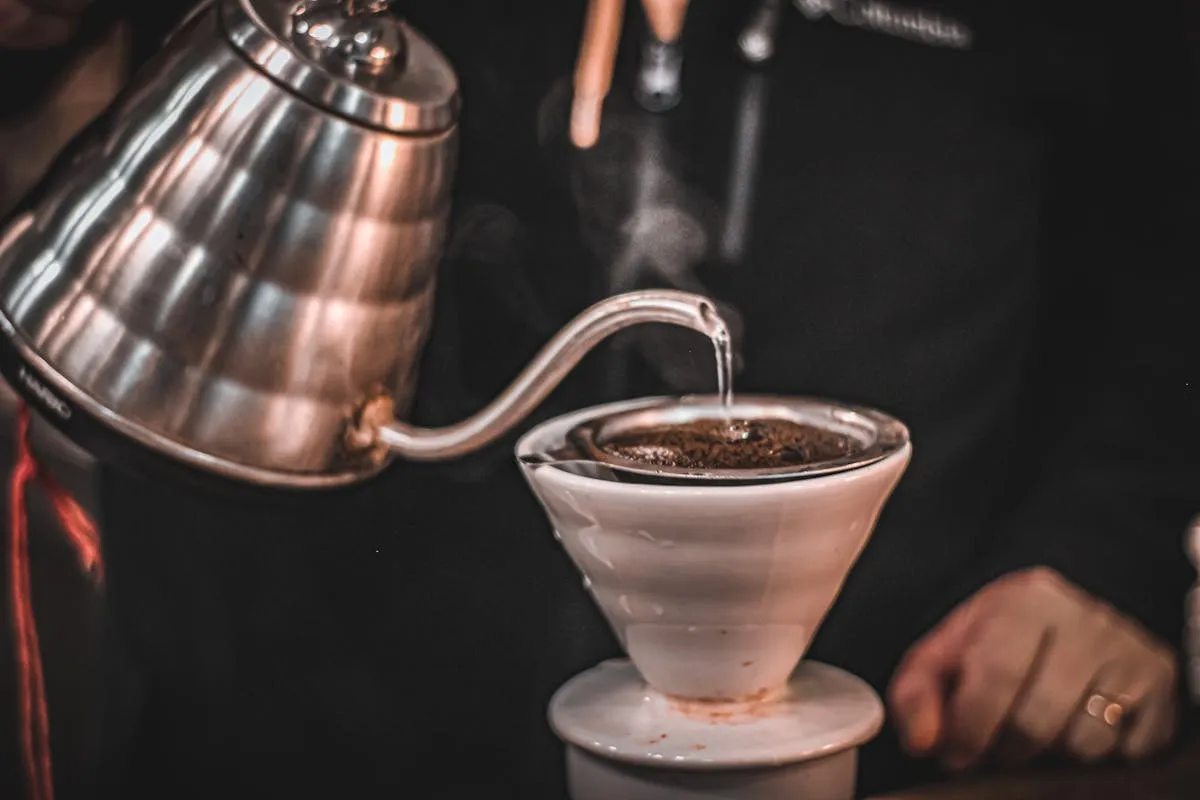 Clear water being poured into a kettle beside Ethiopian coffee beans, illustrating how water quality shapes coffee flavour