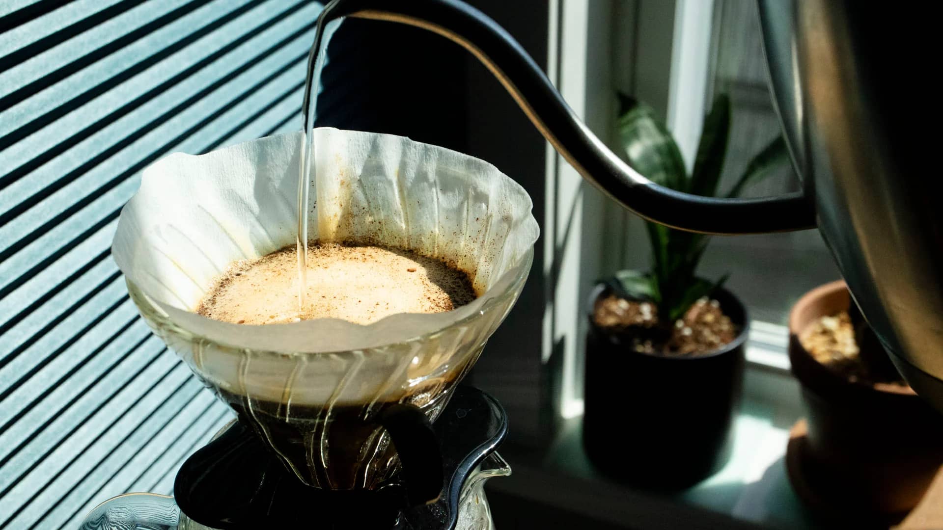 Pour over dripper brewing Ethiopian single-origin coffee into a glass server, showing a golden stream of freshly brewed coffee