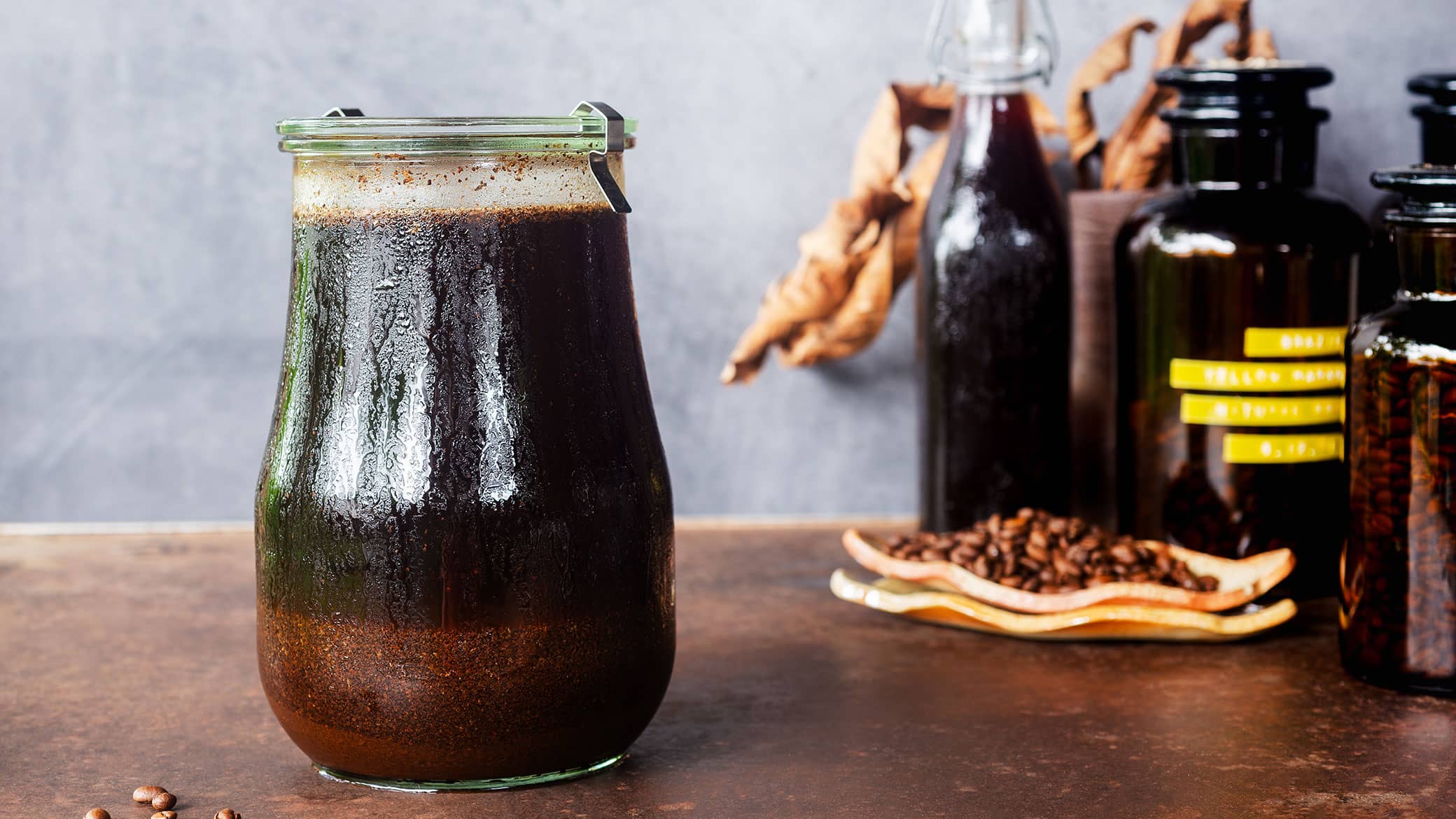 Ethiopian coffee cold brew concentrate in glass pitcher with ice and fresh coffee beans